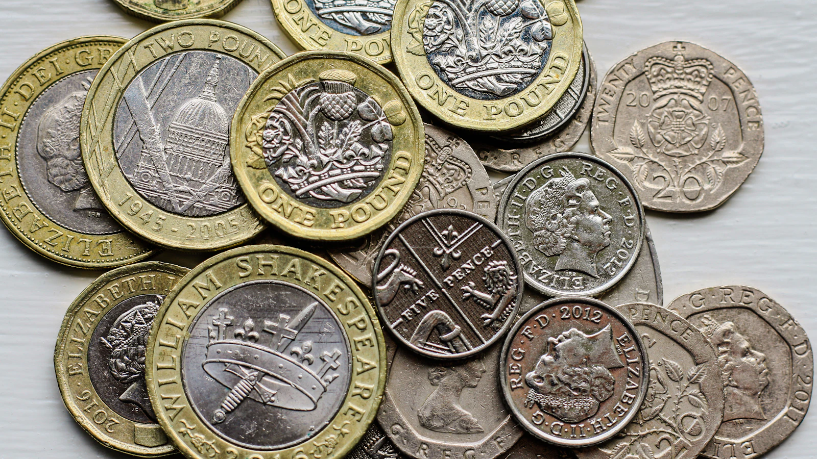 A pile of British coins sitting on top of a table