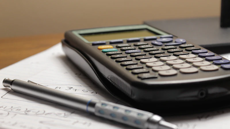 A mechanical pencil resting on a handwritten worksheet beside a scientific calculator on a desk