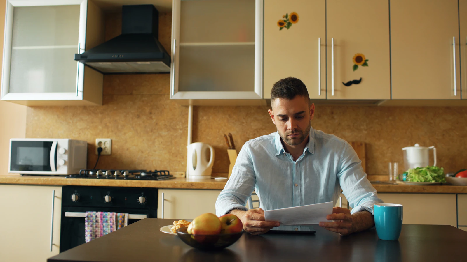 A man reading a document at a kitchen table with coffee